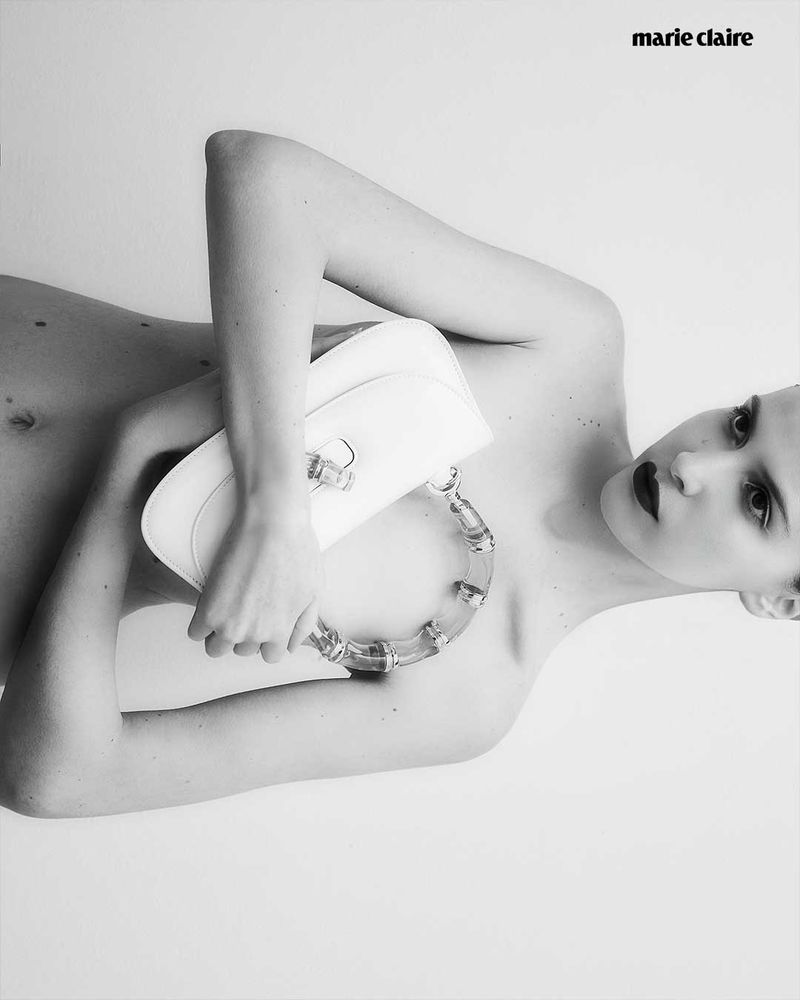 Black and white fashion portrait featuring a fair-skinned adult woman holding a white purse. 'Marie Claire' logo visible in the upper right.