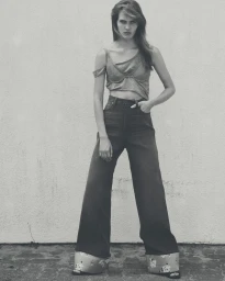 Model in dark high-waisted wide-leg jeans with floral cuffs and a grey crop top standing against a neutral wall