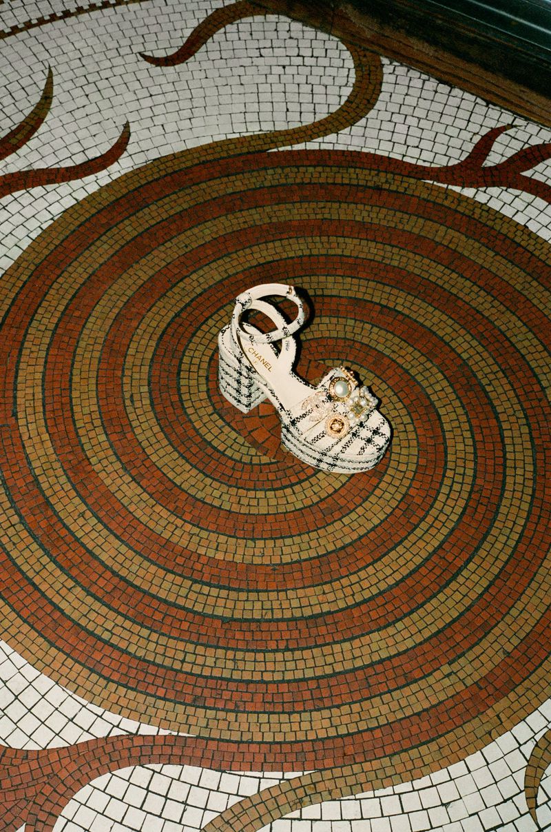 Overhead shot of a platform heel sandal decorated with embellishments on a mosaic tiled surface with a spiraling pattern.