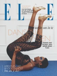 Model lying on the floor in a black lace catsuit with legs elevated against a white panel wall by photographer Tobias Delcroix