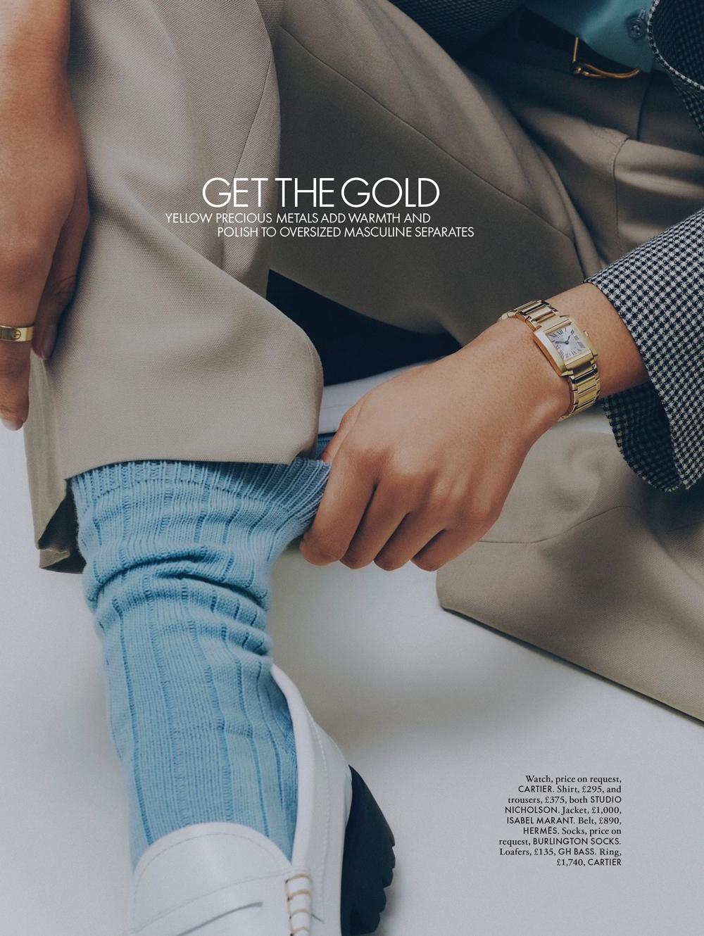 Person wears gold watch and ring, blue ribbed socks, and white loafers in a fashion editorial studio shot for an elevated, stylish look.