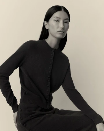 Model Xinyue Guo wearing a dark knit button-up cardigan and matching skirt against a neutral backdrop for Lisa Yang.