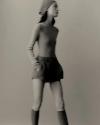 Model wearing a head covering, fitted top, and shorts against a neutral background in a portrait for Lisa Yang Fall Capsule.
