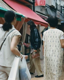 Three individuals walking through a street market with red awnings, captured for the Cordera Fall/Winter 2025 campaign.