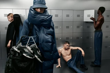 Group of models in a locker room wearing Rains x Umbro collaboration apparel, bucket hat, and holding sneakers.