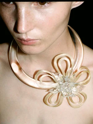 Close-up portrait of a model wearing a large sculptural lucite floral necklace for 10 Magazine Deutsch editorial by Walter Pierre.