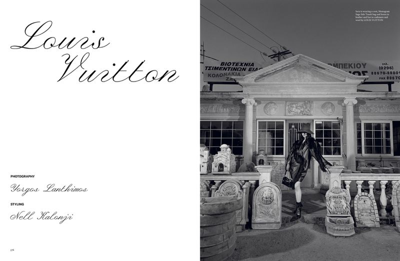 Black and white fashion editorial shot featuring a woman in a hat and coat standing in front of a building with architectural details.