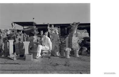 Model Sora Choi seated among stone statues in a sculpture yard for AnOther Magazine by photographer Yorgos Lanthimos