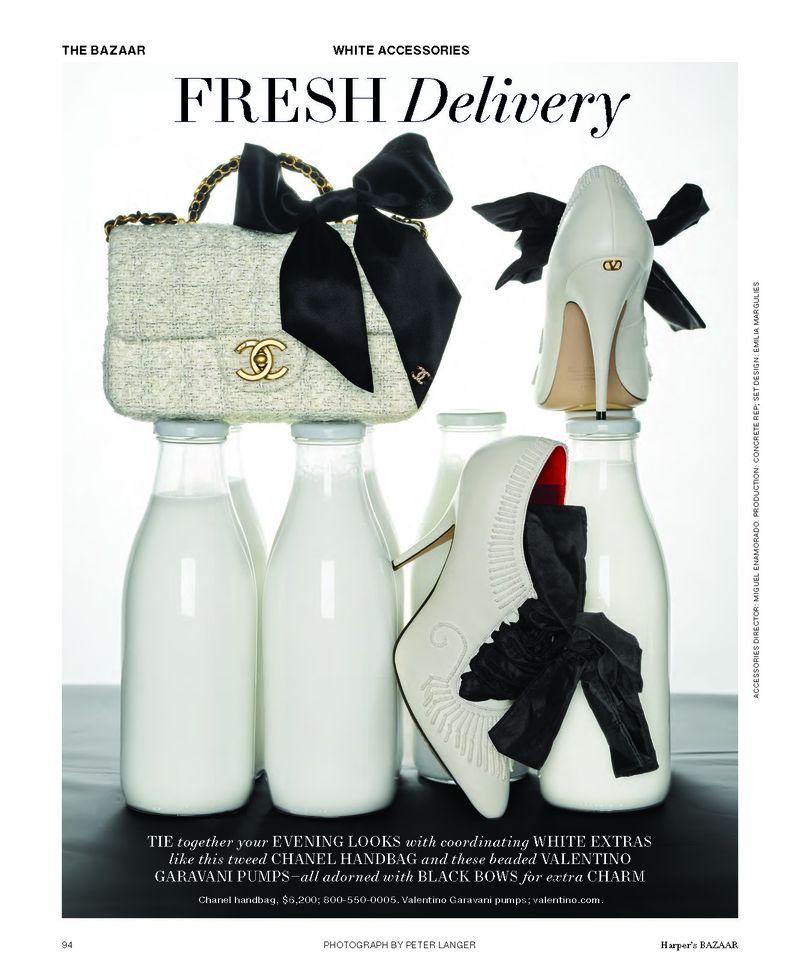 Fashion still life: tweed Chanel handbag with black bow and Valentino Garavani pumps with bows, atop vintage glass milk bottles, studio lit.