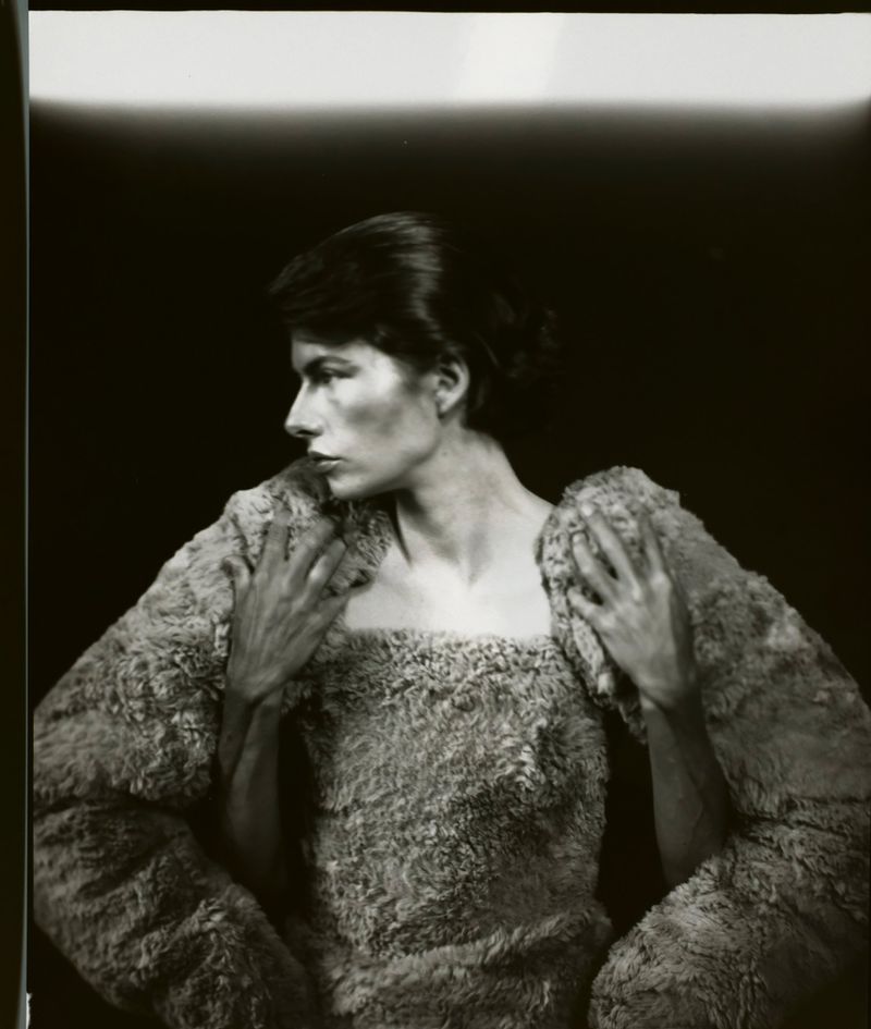 Monochrome portrait of a woman in a textured top, side profile, against a dark background. Soft, diffused lighting and neutral tones.