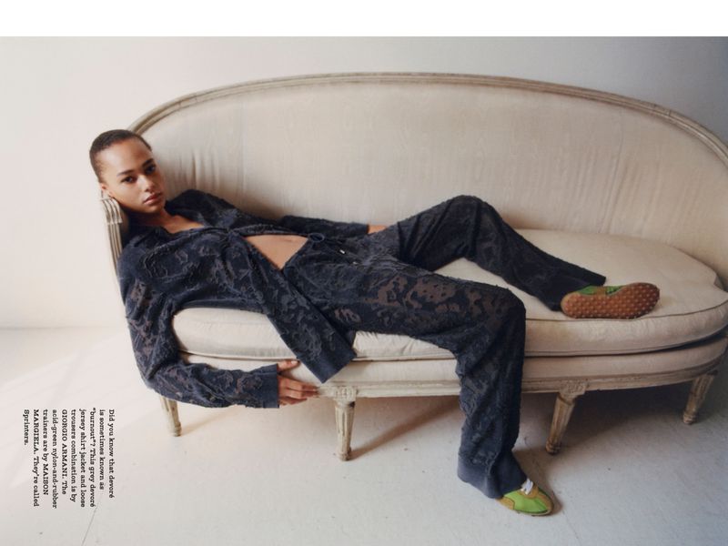 A slender adult female model poses on a light-colored chaise lounge wearing a patterned jacket and matching pants, with green and brown shoes.