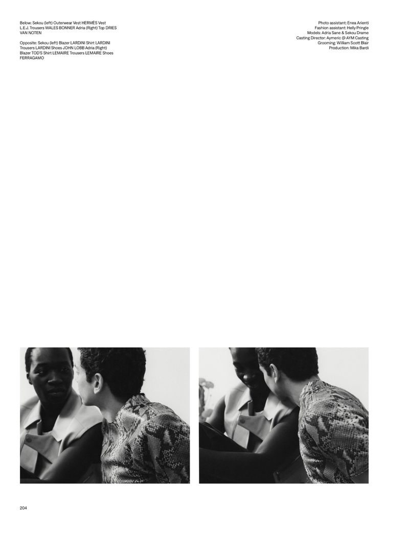Black and white fashion editorial featuring two men in patterned shirts having a discussion indoors under natural lighting.