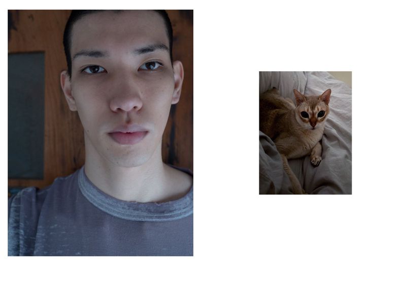 Portrait of an adult Asian male and a light brown cat indoors. A person gazes at the camera beside a wooden door, while the cat rests on a gray blanket.