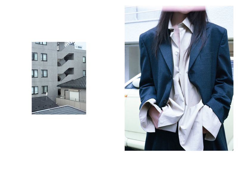 Woman in a suit jacket and blouse stands in front of a car and building in an editorial fashion photograph taken at eye-level.