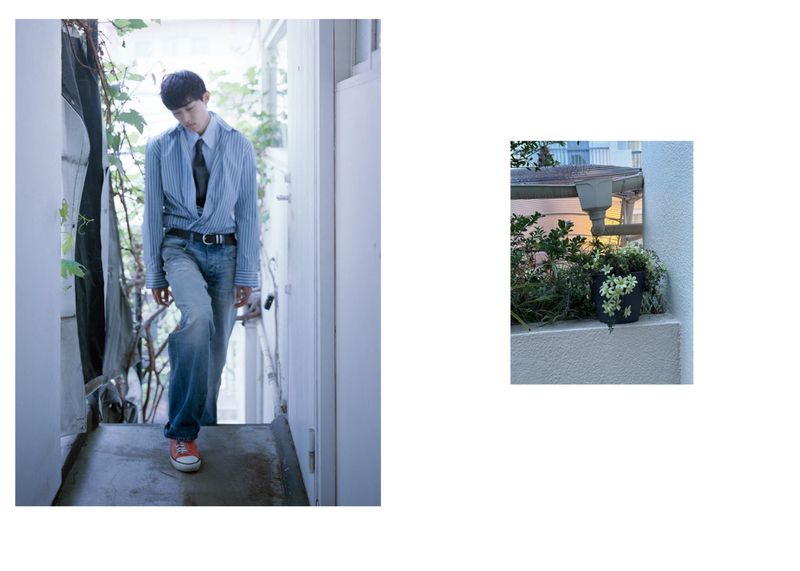A young adult man in a blue shirt and jeans walks down a hallway in a fashion style photoshoot, indoor environment, casual, cool mood.