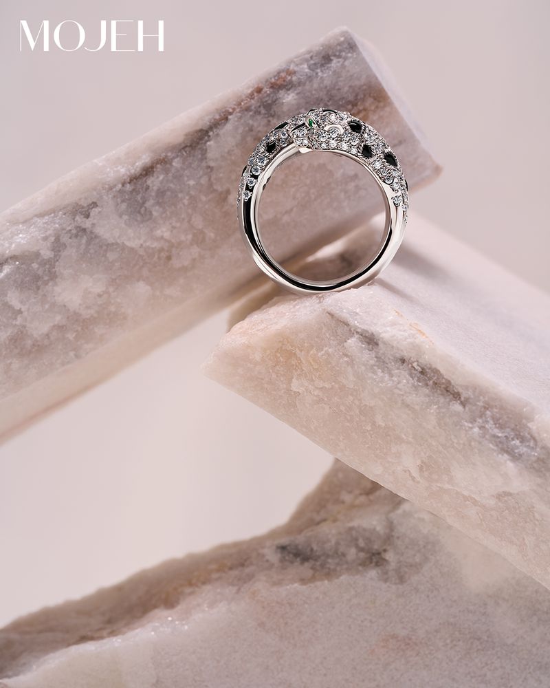 Close-up shot of a silver ring with stones on a marbled stone surface, product photography showcasing jewelry.