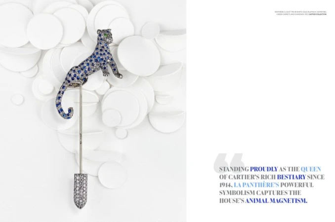 Elegant brooch featuring a jeweled panther design in blue and white stones, set against a backdrop of arranged white circular shapes.