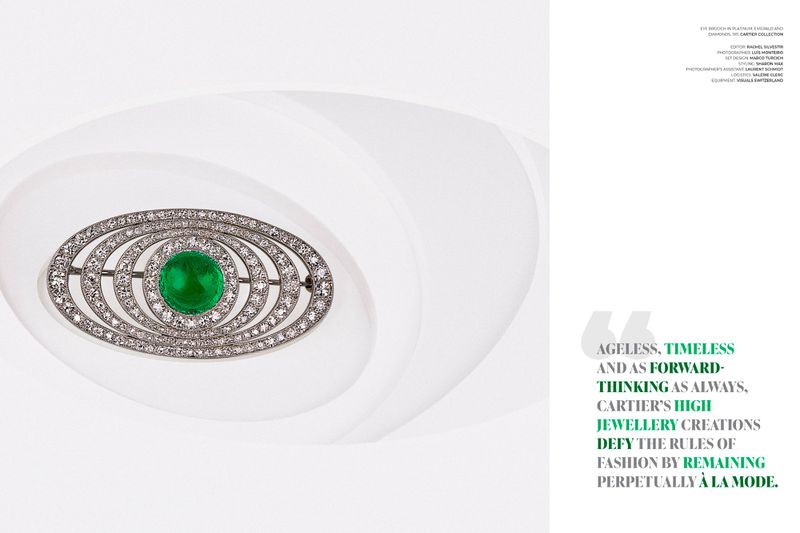 Elegant oval-shaped brooch features a central green gemstone surrounded by diamonds, displayed against a soft white backdrop.