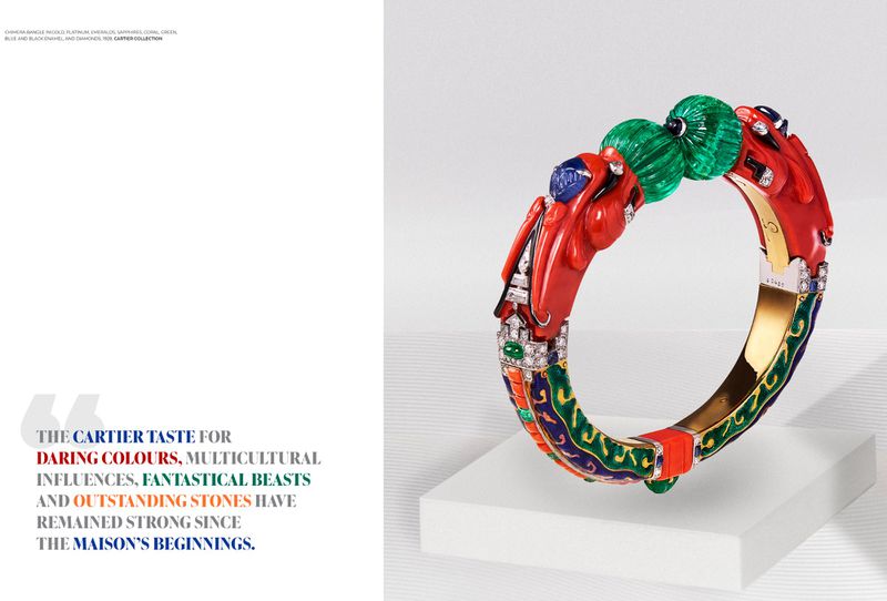 Exquisite multicolored Cartier bracelet with emeralds, sapphires, coral, and diamonds on a white platform against a light backdrop.