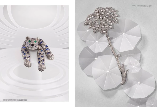 Close-up of two bejeweled brooches, one a tiger motif with blue stripes and the other a floral arrangement on a white backdrop.
