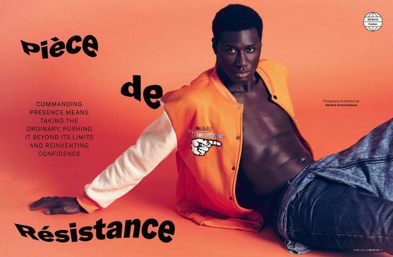 Fashion shot of an adult Black male model lying down in an orange jacket and jeans against an orange studio backdrop with text overlays.