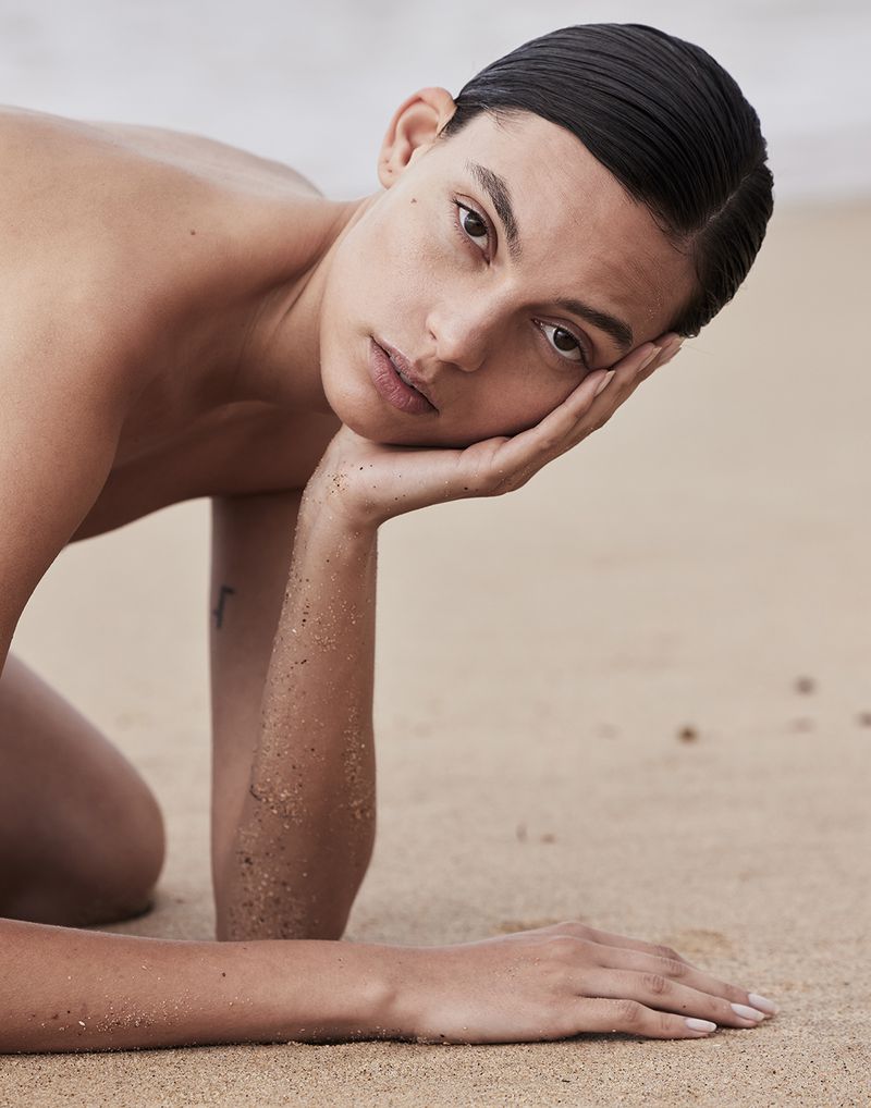 Charlee Fraser posing on a sandy beach resting head on hand for Harper's Bazaar Australia shot by Justin Woo.