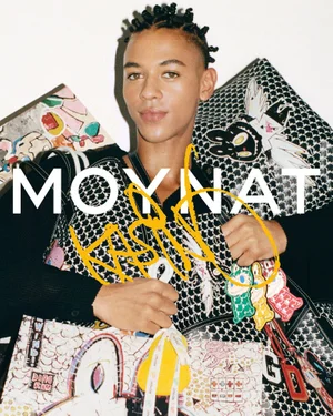 Guillaume Diop poses holding patterned Moynat bags with Kasing Lung cartoon patches against a white background.