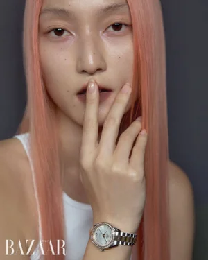 Model with long pink hair wearing a silver watch and white top posing for Harper's Bazaar Korea