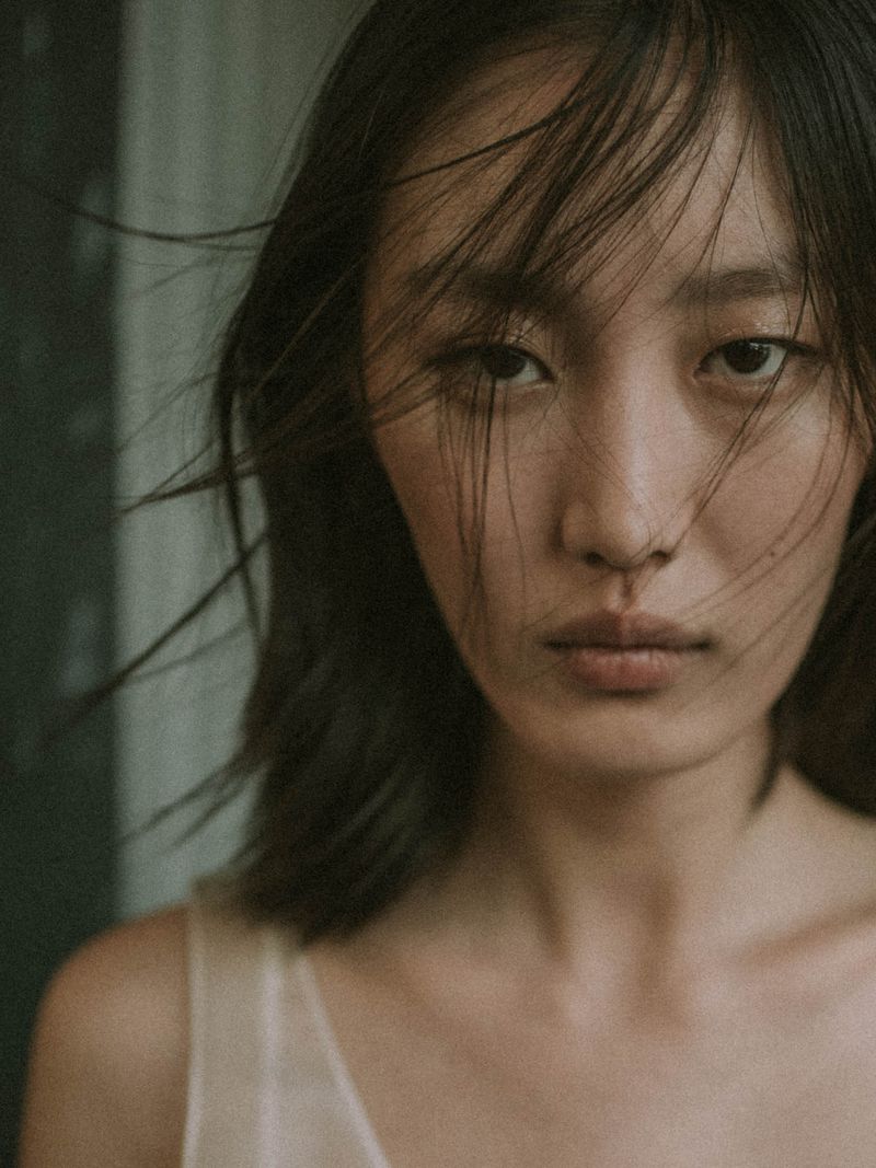 Close-up portrait of model Xiru Yang with wisps of hair across her face backstage at Jason Wu SS26.