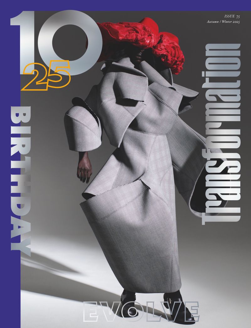 Fashion magazine cover featuring a full-length figure in an oversized grey coat with red hair against a gradient background.