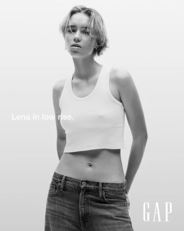 Black and white studio portrait of a young adult female fashion model wearing a tank top and jeans in a GAP ad.