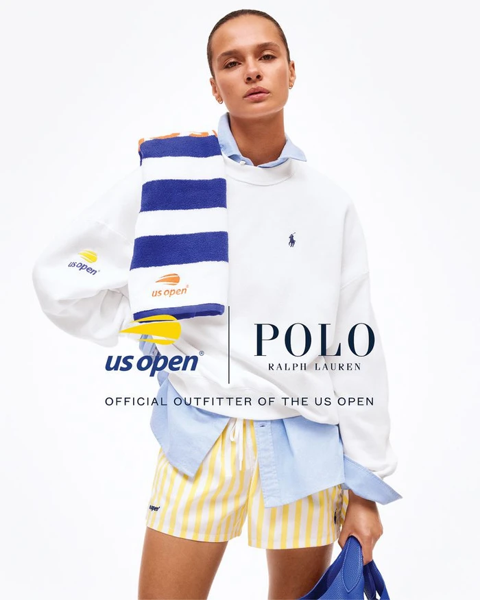 Model in white sweatshirt, blue striped towel, and yellow striped shorts against a plain white background for the US Open.