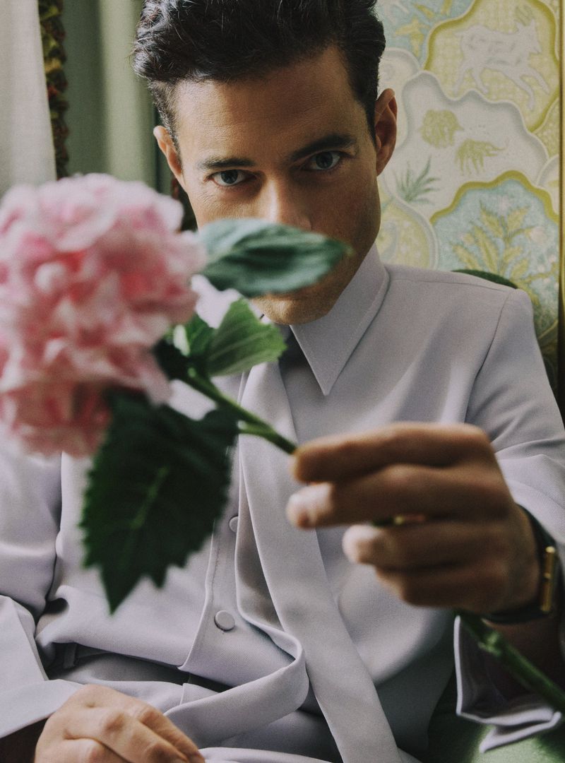 Portrait of a man in a suit holding a pink hydrangea, showcasing a formal yet natural aesthetic with soft lighting and floral accents.