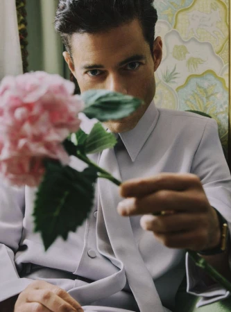 Portrait of a man in a suit holding a pink hydrangea, showcasing a formal yet natural aesthetic with soft lighting and floral accents.