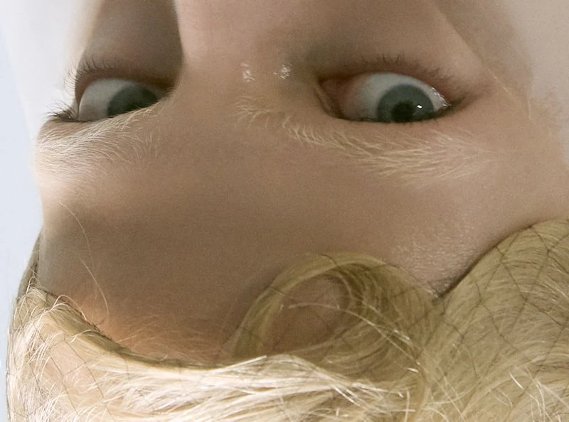 Macro studio shot of a fair-skinned face with light blonde hair, eyes looking up, captured in a dramatically close-up, overhead framing.