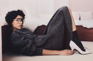 Model wearing a grey knit dress and glasses reclining on the floor for Marie Claire UK editorial