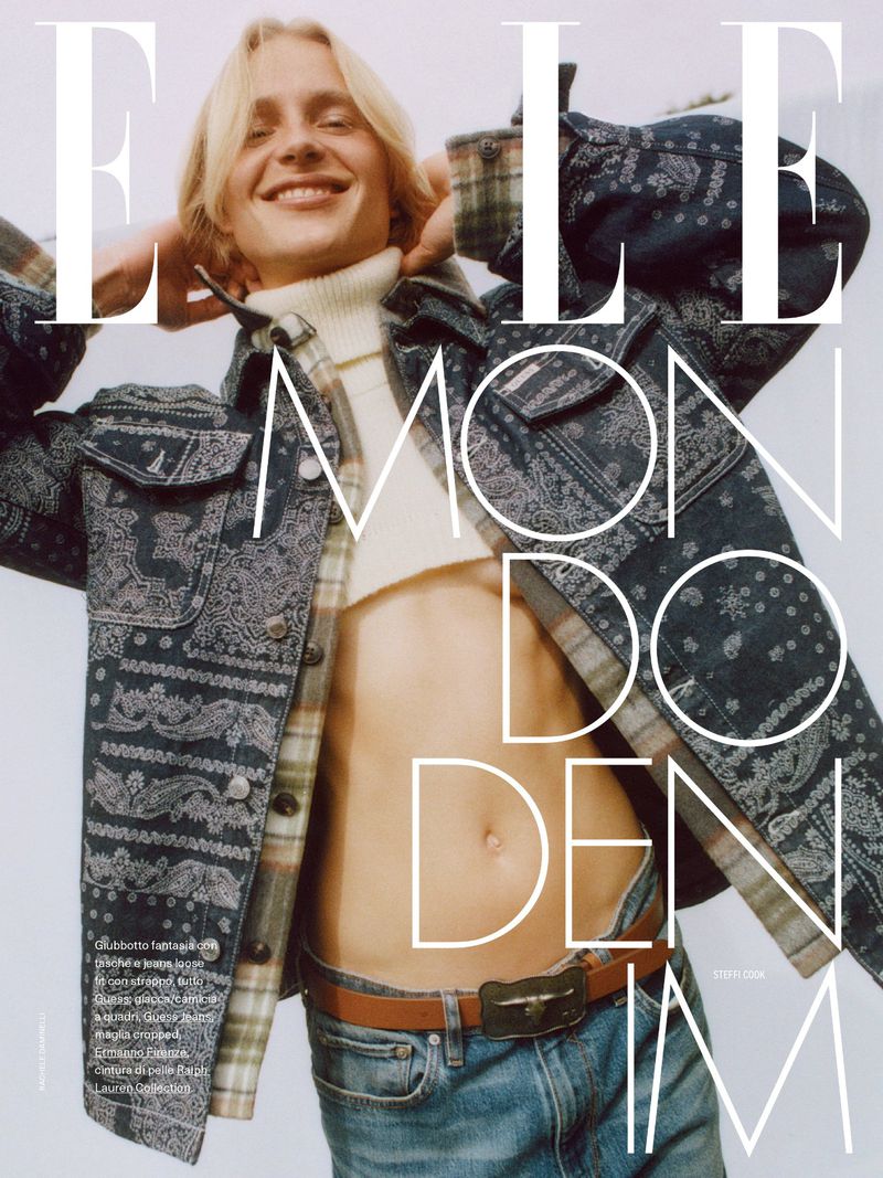 Fashion editorial shot of a smiling blonde male model wearing a blue paisley jacket and jeans, with the 'ELLE' magazine logo overlaid.