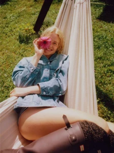 Model Steffi Cook in denim jacket resting in hammock while holding a pink flower across her eye, for Elle Italia Mondo Denim project.