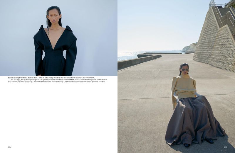 Fashion editorial shot on location of a woman wearing a yellow top and gray skirt sitting near the ocean with architectural features.