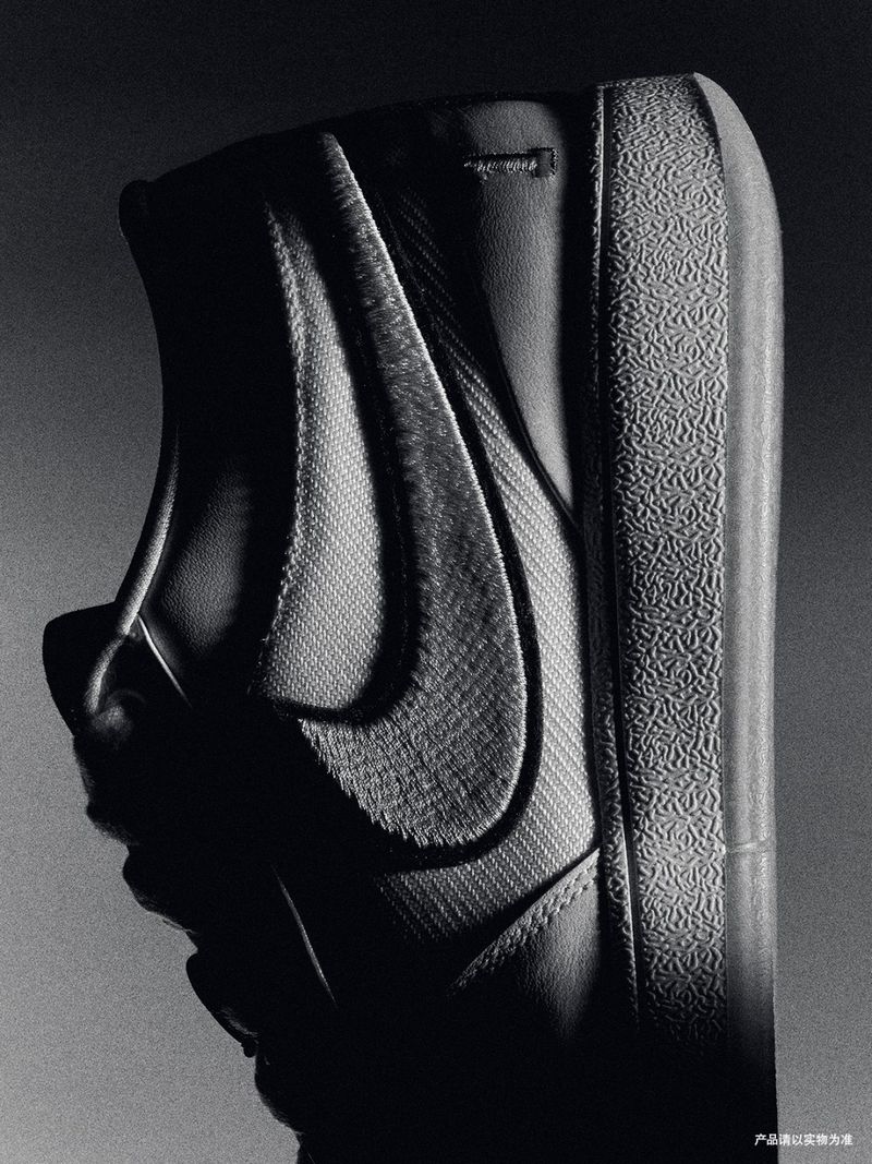 Monochromatic close-up shot of a black and gray Nike Blazer sneaker featuring the iconic Swoosh logo and textured rubber sole.