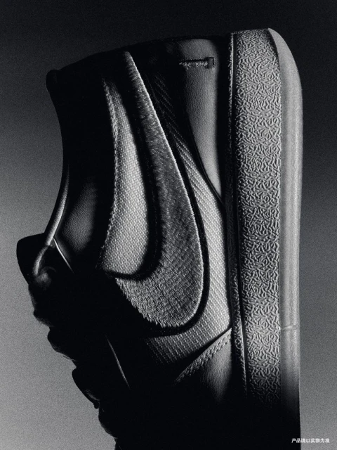 Monochromatic close-up shot of a black and gray Nike Blazer sneaker featuring the iconic Swoosh logo and textured rubber sole.