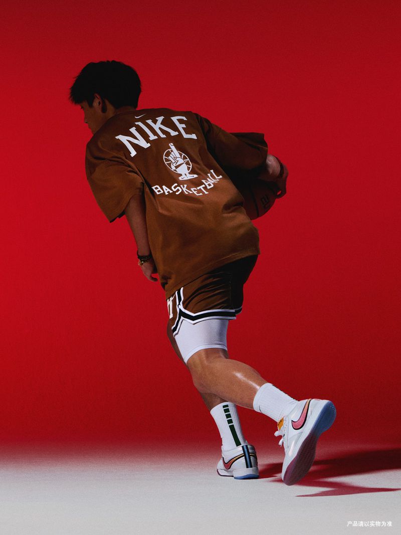 Male model in brown Nike basketball outfit against a red backdrop, posing dynamically to showcase sports fashion apparel.
