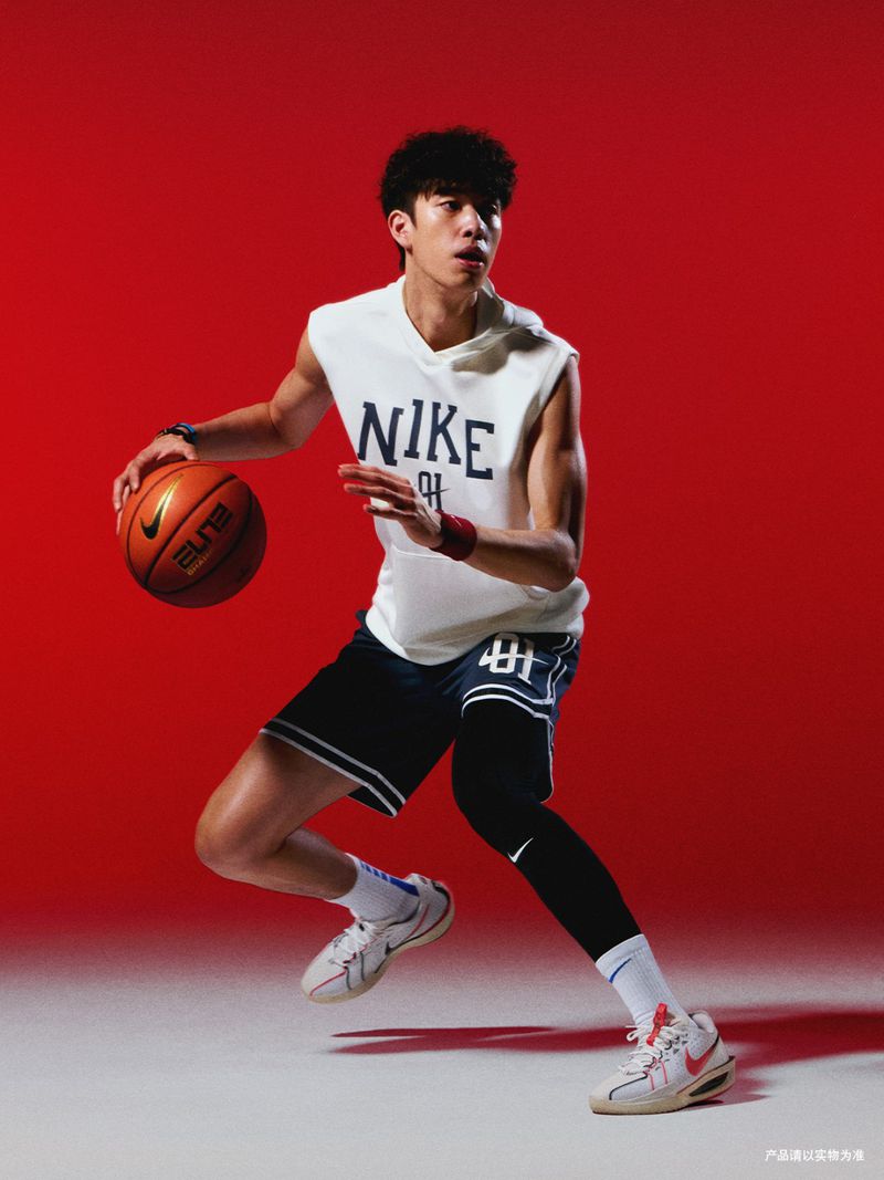 Athletic man in a sleeveless Nike shirt dribbles a basketball against a vibrant red backdrop, capturing the energy of sports.