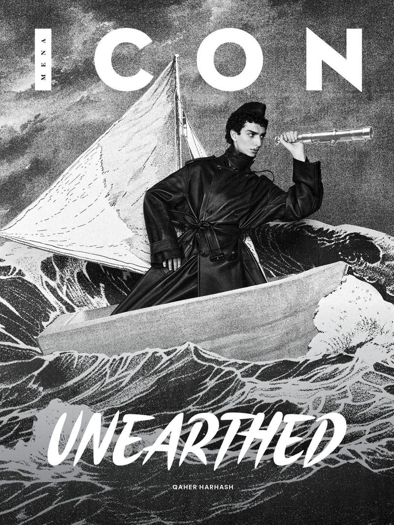 Fashion magazine cover features a man in a boat with a sail, holding a spyglass against a monochrome water and sky background.