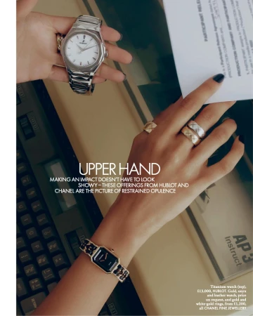 Close-up of a person's hands showcasing luxury watches and rings, featuring metallic and gold jewelry against a neutral background.