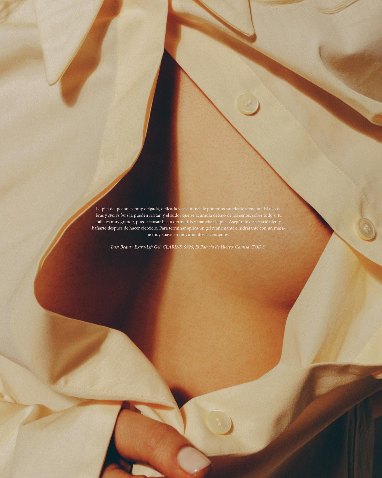 Close-up studio shot of a woman's upper chest and an open, unbuttoned off-white shirt with a hint of light brown skin visible.