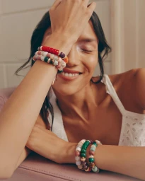 Model smiling with beaded bracelets on both wrists for Net-A-Porter Fine Jewellery FW21