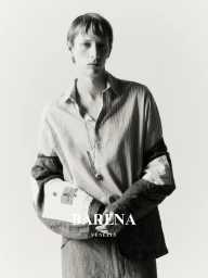 Monochrome portrait of a male model wearing a striped button-down shirt and structured jacket against a plain light background.