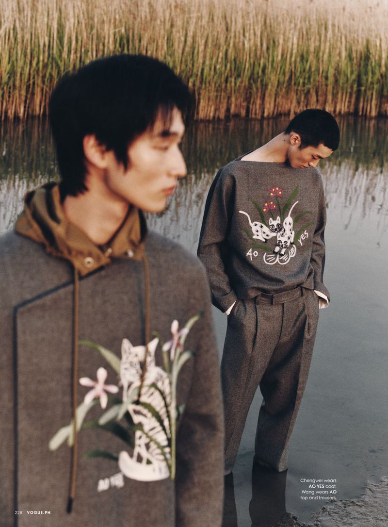 Two Asian male models in an outdoor setting. One model is wearing a grey sweatshirt and trousers and the other is wearing a grey hoodie.