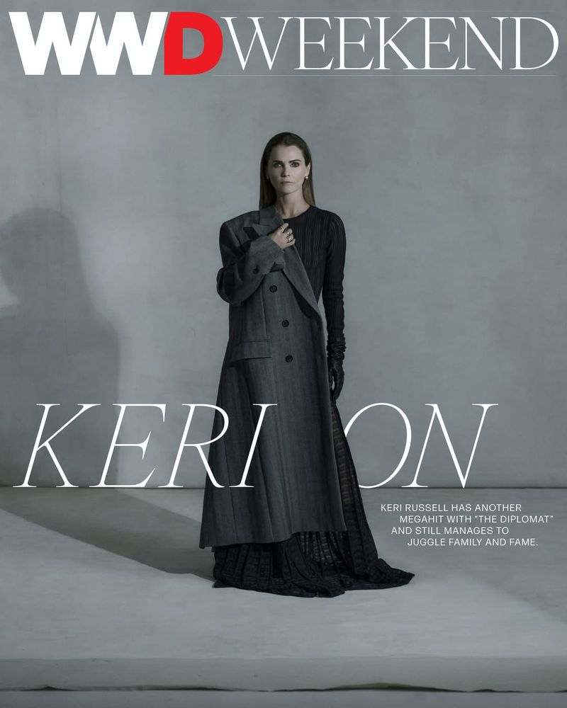 Fashion magazine cover featuring a full-length shot of Keri Russell wearing a dark dress and a grey coat against a gradient grey background.